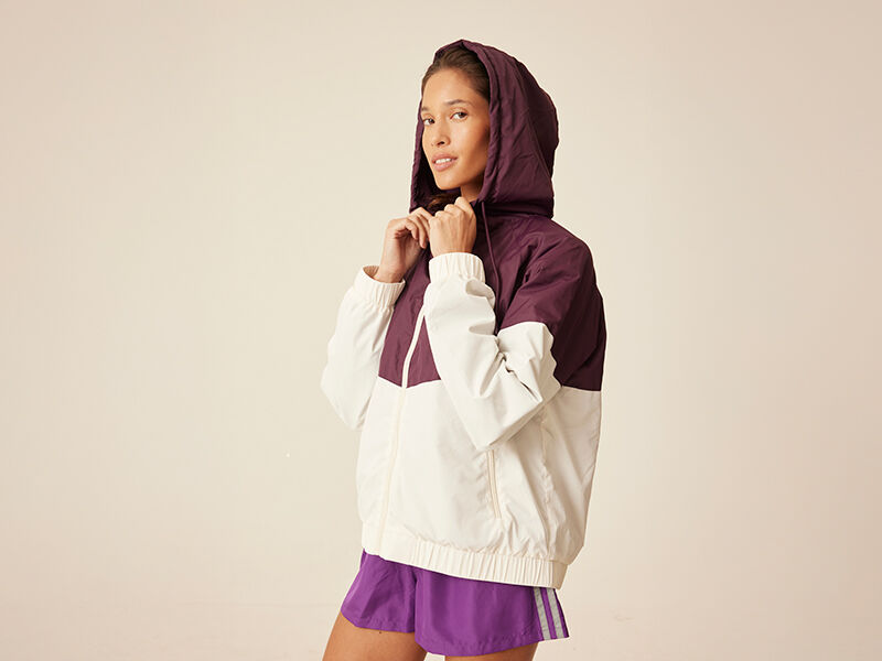 Modelo usando jaqueta com capuz em tons roxo e branco