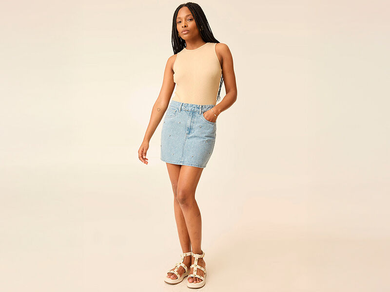 Modelo feminina usando saia jeans e sandálias