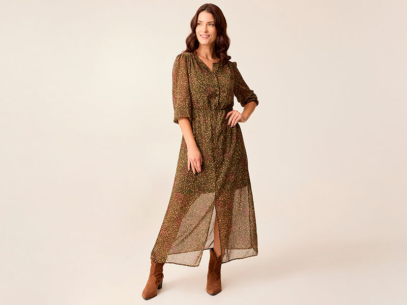 Mulher com vestido longo boho e botas em fundo neutro