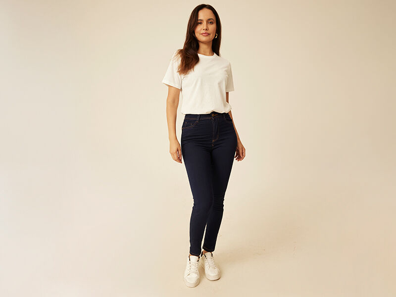 Modelo vestido com camiseta branca e jeans azuis.