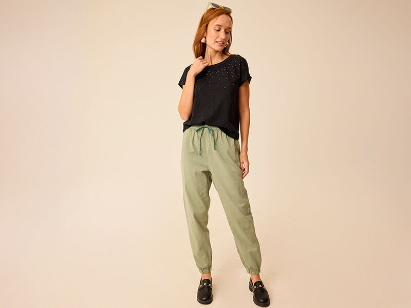 Mulher vestindo camiseta preta e calça verde