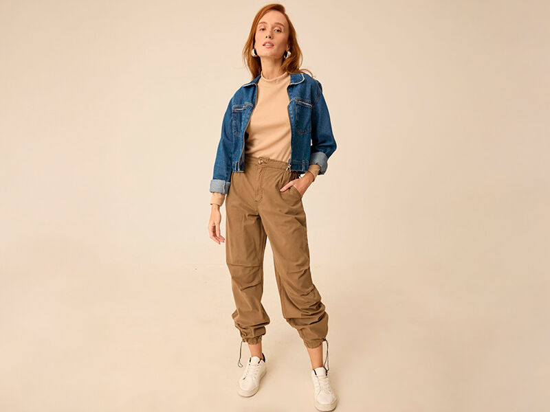 Mulher posando com jaqueta jeans e calça cargo.