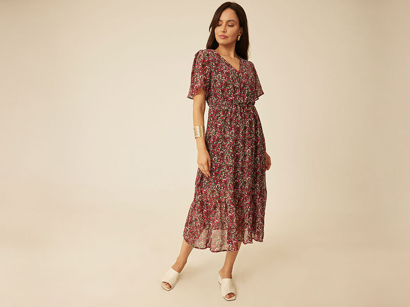 Mulher usando vestido florido com sandálias brancas