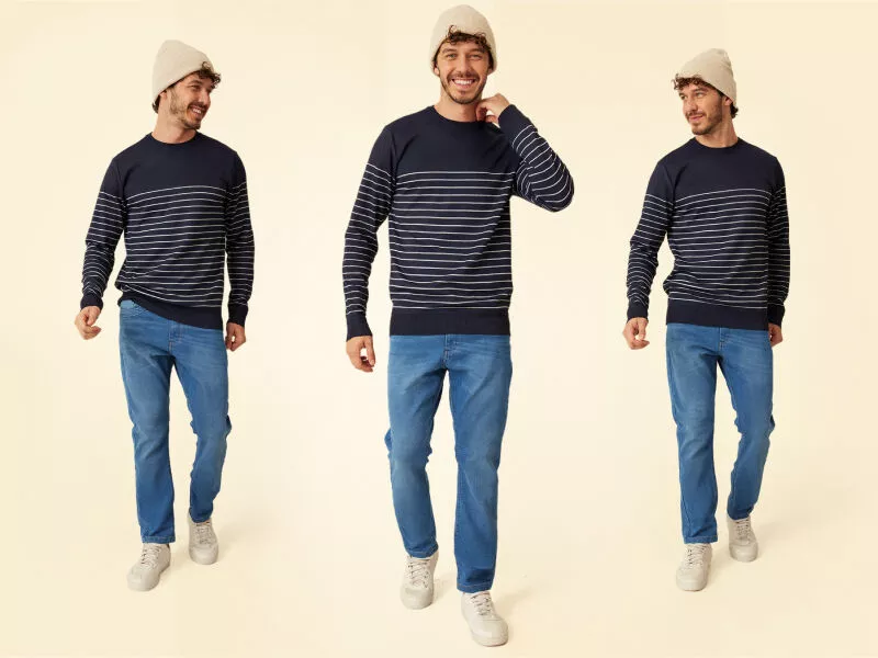 Homem sorridente usando suéter listrado e calça jeans