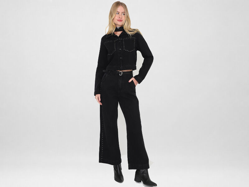 Mulher posando com look preto moderno e estiloso.