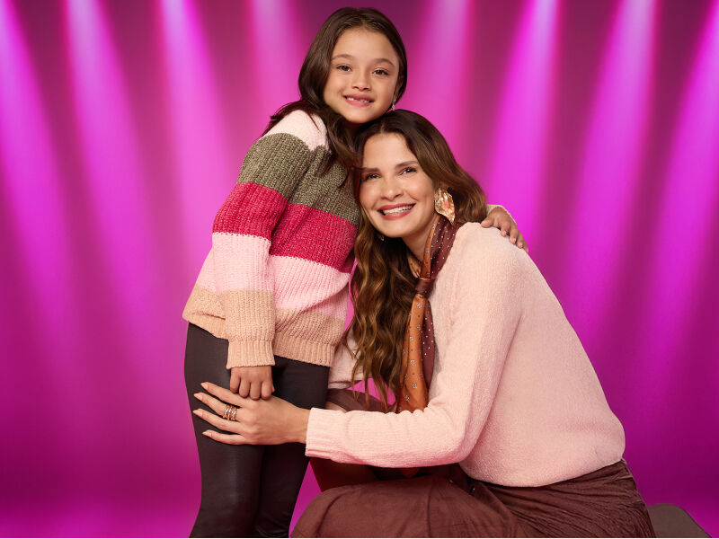 Mãe e filha sorrindo com suéteres coloridos