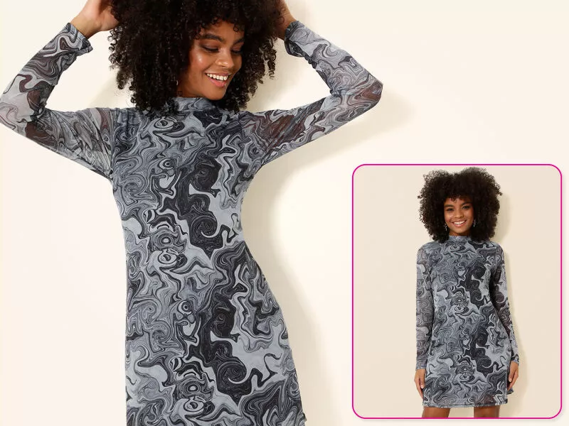 Mulher sorrindo com vestido estampado em preto e cinza.