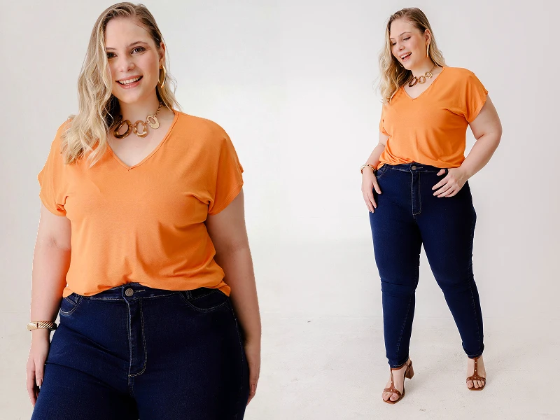 Mulher plus size sorridente veste t-shirt laranja e calças de ganga azuis escuras. Look casual de moda feminina.