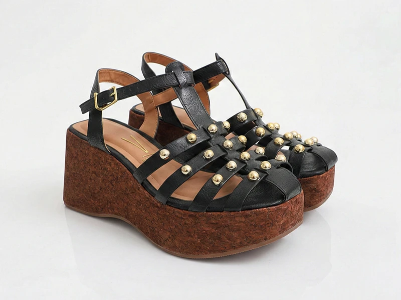 Sandálias plataforma pretas com tachas douradas e sola de cortiça.