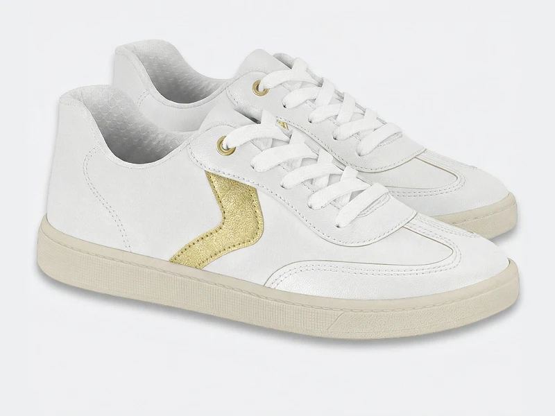 Ténis brancos com detalhe lateral dourado, atacadores brancos e sola bege clara.