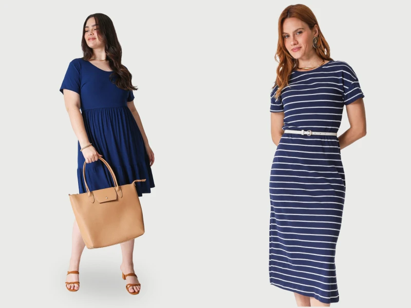 Duas mulheres com vestidos azul-marinho: um curto liso com mala bege e outro midi às riscas com cinto branco.
