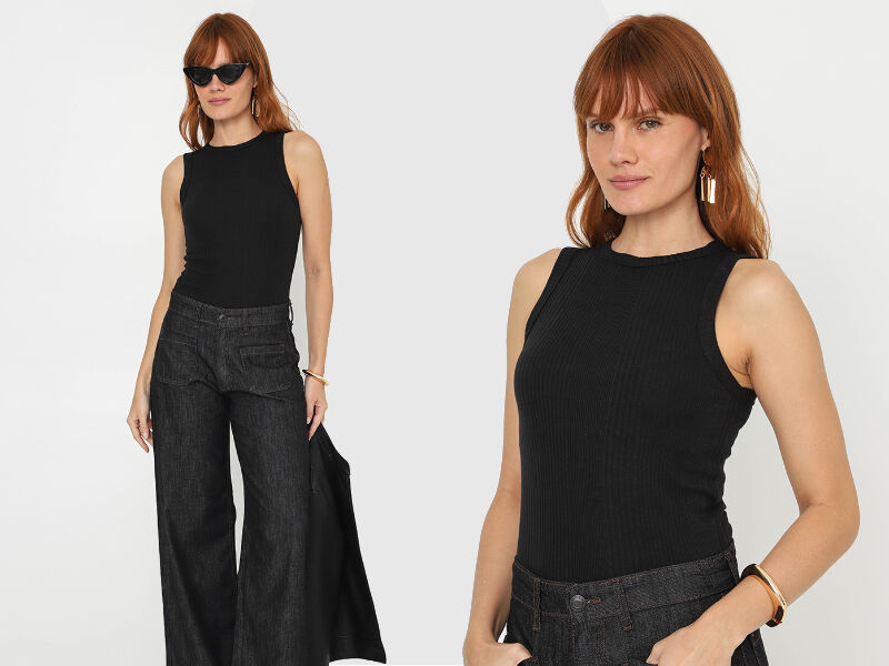 anos90 2 Mulher com blusa preta e calça larga em fundo branco.