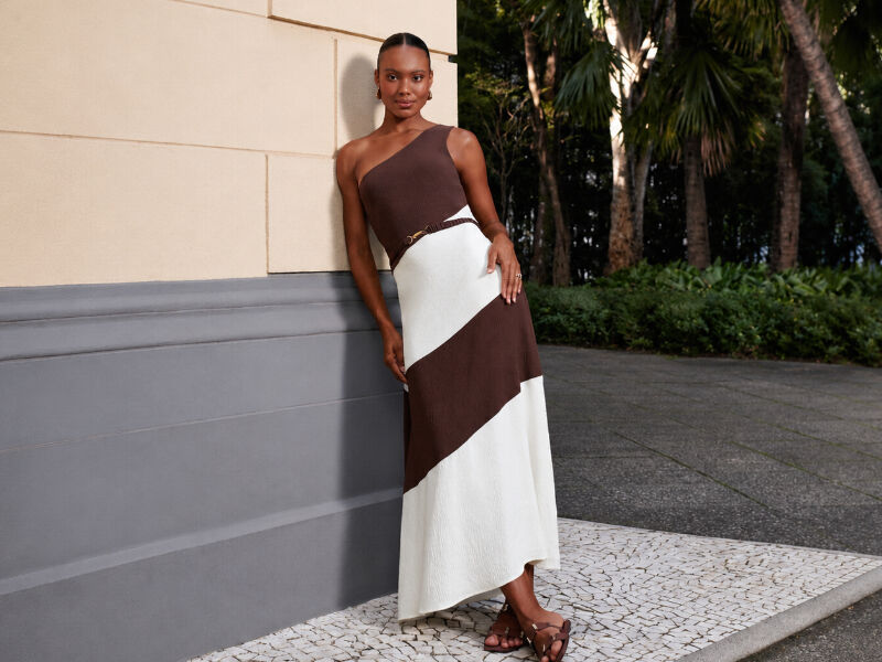 Modelo em vestido longo com detalhes em marrom e branco.