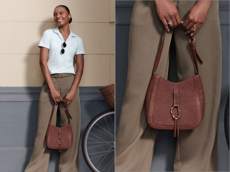 Mulher sorridente segurando bolsa de couro marrom.